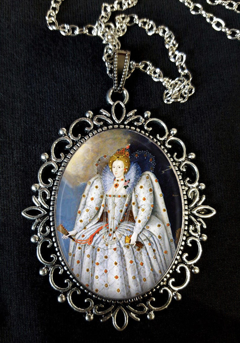 May include: A silver pendant necklace with an oval cameo featuring a portrait of Queen Elizabeth I in a white and gold gown. The cameo is set in a silver filigree frame.