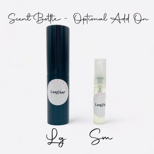 May include: Two glass bottles with spray tops. The larger bottle is black with a white label that says "Secret Trend Leather". The smaller bottle is clear with a white label that says "Secret Trend Leather". The bottles are labeled "Lg" and "Sm" respectively.