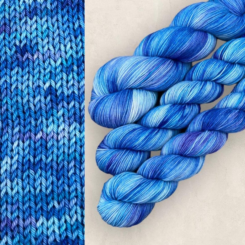 May include: Image of blue yarn skeins with a mix of blue and white shades. The yarn is arranged diagonally, highlighting the texture and colour variations. A knitted swatch of the same yarn is also visible.