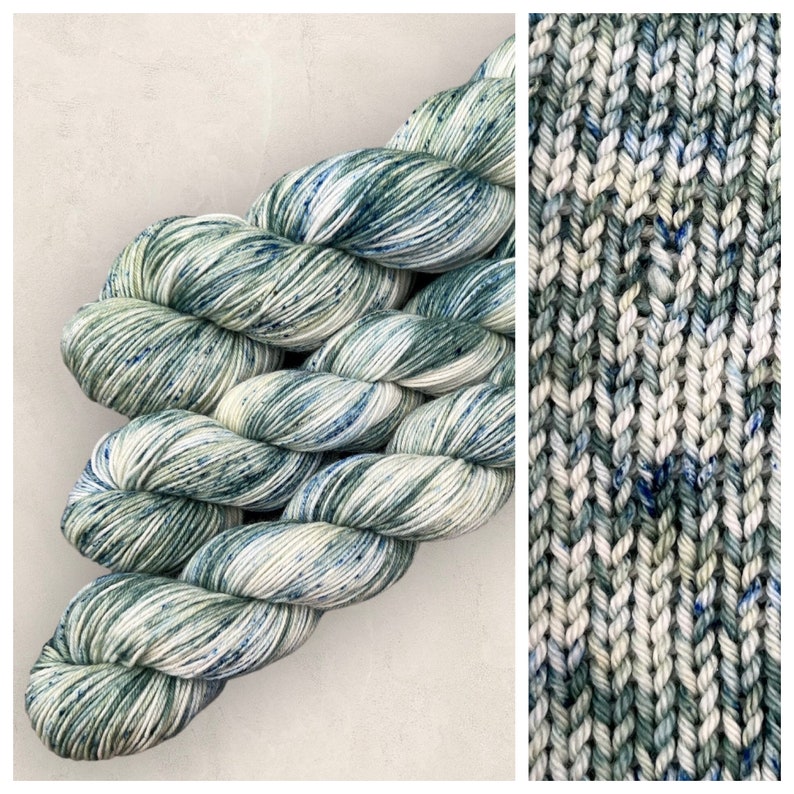May include: Skeins of yarn in shades of green, white, and blue. The yarn is speckled with blue and green flecks. The yarn is shown in a skein and knitted into a fabric.