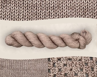 Könnte beinhalten: Nahaufnahme eines Strangs hellbraunen Garns, präsentiert mit Strick- und Häkelstoffmustern. Das Garn ist gezwirnt, mit einem weichen Aussehen und leichtem Glanz. Die Strickmuster zeigen verschiedene Stichmuster und heben die Textur und Farbe des Garns hervor.