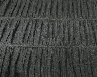 May include: Black fabric with a gathered, pleated texture. The fabric is soft and has a subtle sheen.