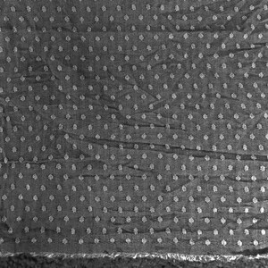 May include: A close-up of a black fabric with a white polka dot pattern. The fabric has a textured surface and a slightly wrinkled appearance.