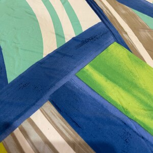 May include: Abstract geometric pattern fabric with blue, green, white, and brown stripes and shapes.