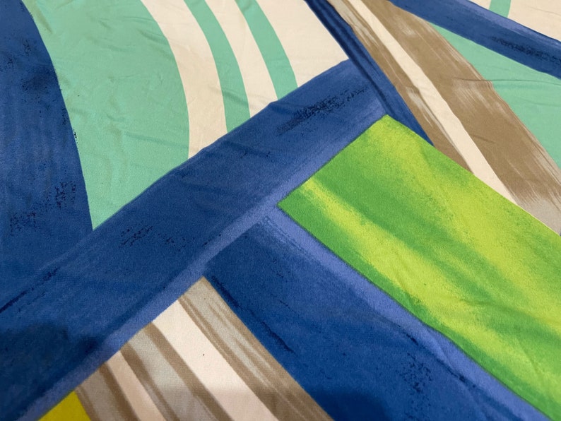 May include: Abstract geometric pattern fabric with blue, green, white, and brown stripes and shapes.