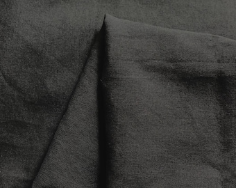 May include: Close-up of a dark gray fabric with a textured surface. The fabric is folded in half, creating a crease down the center.
