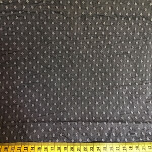 May include: Black fabric with a white polka dot pattern. A yellow measuring tape is at the bottom of the image with numbers 10 through 32.