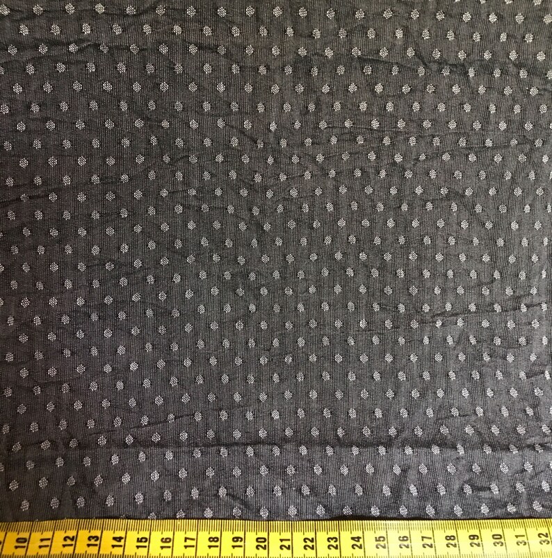 May include: Black fabric with a white polka dot pattern. A yellow measuring tape is at the bottom of the image with numbers 10 through 32.