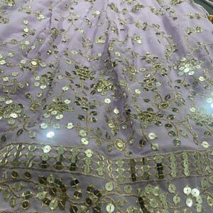 May include: A lavender skirt with gold embroidery and sequins. The skirt has a floral pattern and a layered design.