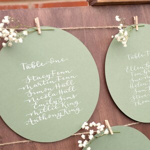 Sage green table plan card | Handwritten calligraphy | Circular seating chart | On the day wedding detail | Hand lettered rustic decor