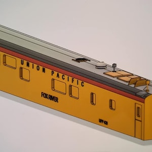May include: A yellow and red model train car with the words "UNION PACIFIC" and "FOX RIVER" printed on the side. The car has a gray roof and several windows.