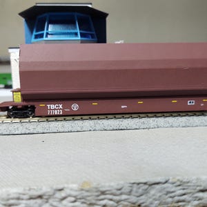 May include: A brown model train car with the text "TBCX 777023" printed on the side.