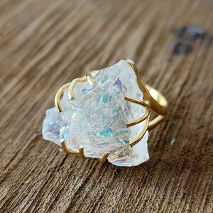 May include: A gold ring with a large, clear, iridescent crystal set in a wire cage design.