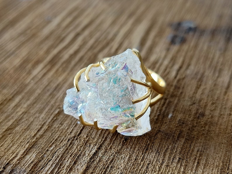 May include: A gold ring with a large, clear, iridescent crystal set in a wire cage design.