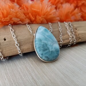 May include: A silver chain necklace with a teardrop-shaped blue and white gemstone pendant.