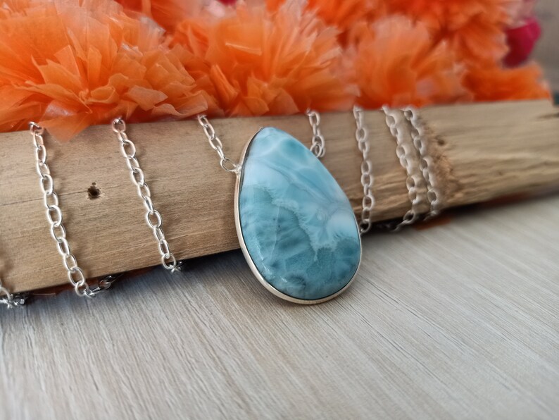 May include: A silver chain necklace with a teardrop-shaped blue and white gemstone pendant.