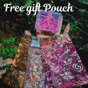 May include: A set of three sheer fabric gift pouches with floral patterns in gold, blue, and pink. The pouches are tied with gold ribbon and have a small clear plastic box with red paper confetti inside. The text "Free gift Pouch" is written in white on a black background.