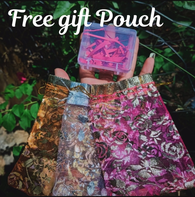 May include: A set of three sheer fabric gift pouches with floral patterns in gold, blue, and pink. The pouches are tied with gold ribbon and have a small clear plastic box with red paper confetti inside. The text "Free gift Pouch" is written in white on a black background.
