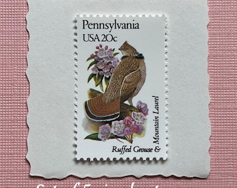May include: A postage stamp featuring a brown ruffed grouse and pink mountain laurel flowers. The text reads Pennsylvania, USA 20c, and Ruffed Grouse & Mountain Laurel. The stamp is mounted on a white scalloped card. This is a set of 5 single stamps.