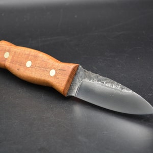 May include: A small, handmade knife with a wooden handle and a dark metal blade. The handle has three brass rivets.