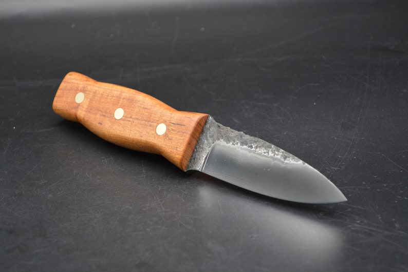 May include: A small, handmade knife with a wooden handle and a dark metal blade. The handle has three brass rivets.