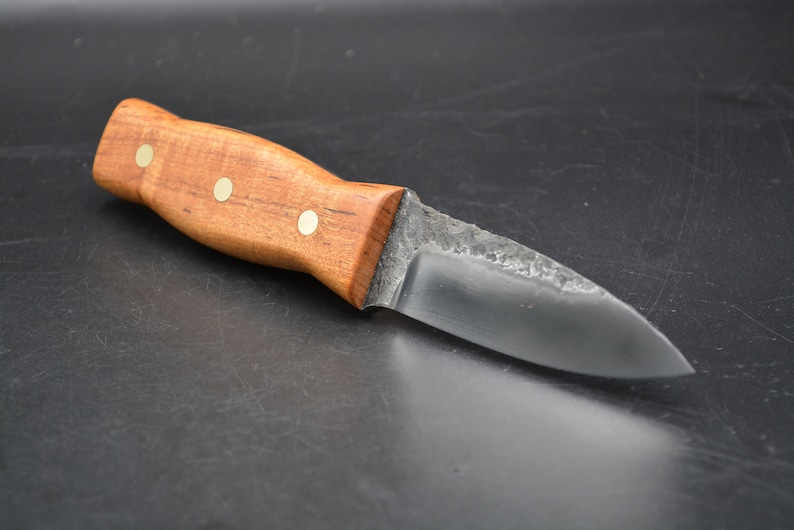 May include: A small, handmade knife with a wooden handle and a dark metal blade. The handle has three brass accents.
