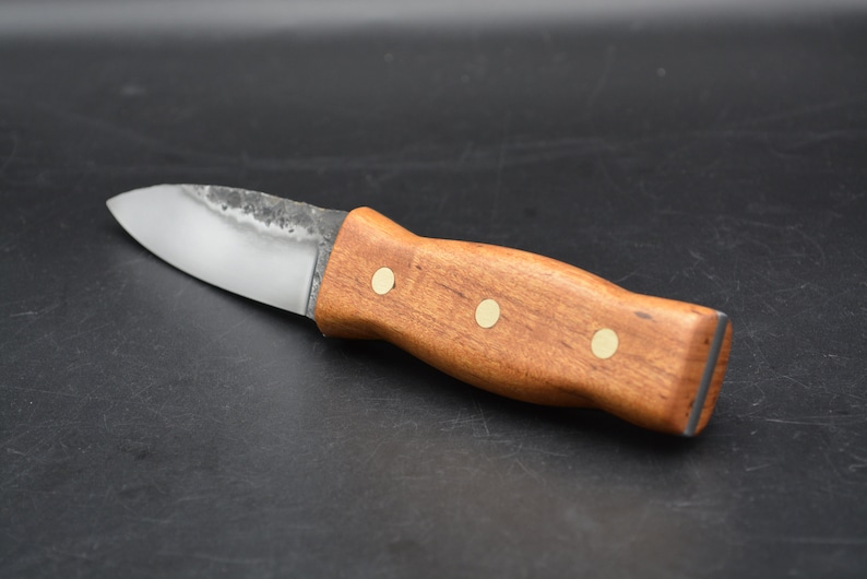May include: A small, handmade knife with a wooden handle and brass accents. The blade is made of steel and has a slight curve.
