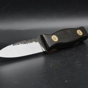 May include: A small, black-handled knife with a silver blade. The handle is made of wood and has two brass accents. The blade has a slightly curved edge.