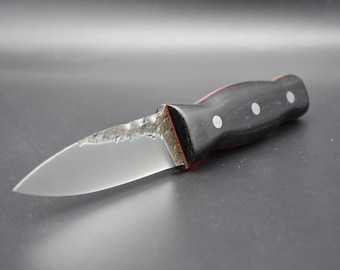 May include: A black and red handled knife with a silver blade. The handle has three white dots.