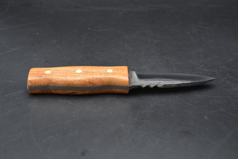 May include: A small, black, serrated knife with a wooden handle. The handle has a dark brown stain and three white dots.