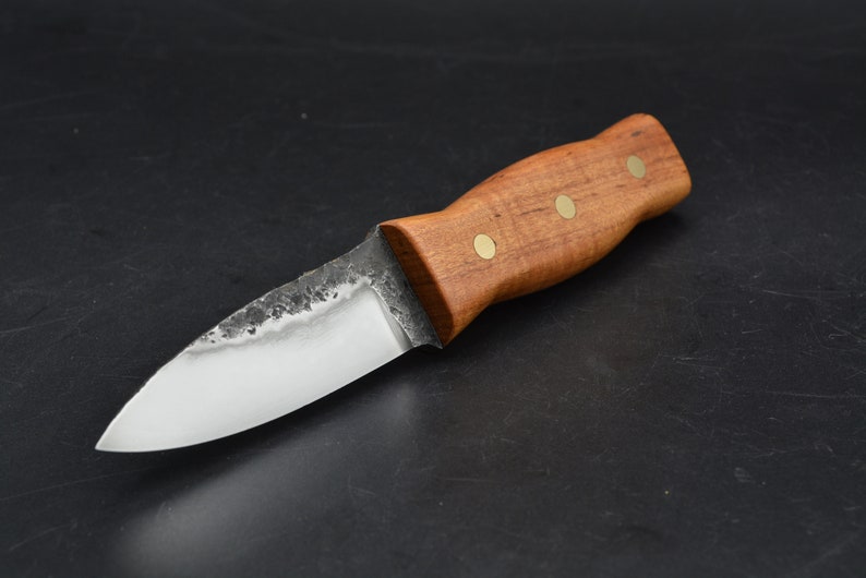 May include: A small, handmade knife with a wooden handle and brass accents. The blade is made of steel and has a slightly curved edge.