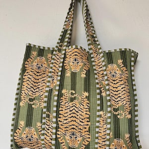 Può includere: Una borsa tote verde con un motivo ripetuto di tigri. La borsa ha strisce verticali verdi e bianche. Le tigri sono arancioni e nere e la borsa ha manici lunghi.