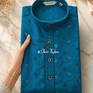 Puede incluir: Kurta bordada de color turquesa con cuello mandarín y cierre de botones. La camisa presenta intrincados calados florales y está etiquetada como "FUBAR Ethnic Wear". El texto "Shree Fashion" también es visible.