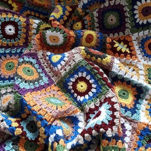 May include: A colorful crocheted blanket with a variety of square patterns in shades of brown, blue, green, yellow, orange, red, and white.