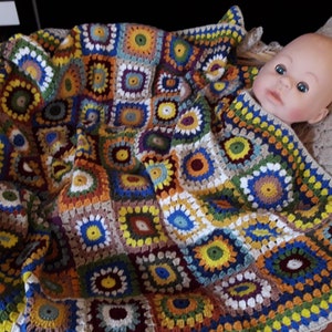 May include: A colorful crocheted baby blanket with a variety of colors and patterns, including squares and circles. The blanket is made with a variety of yarn colors, including brown, white, yellow, green, blue, and red.