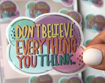 May include: A sticker with a colorful cloud design and the text "Don't believe everything you think." The sticker is printed on clear vinyl and has a glossy finish.