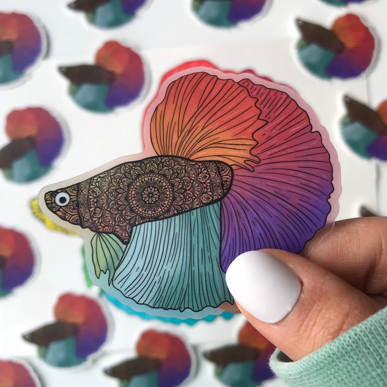 May include: A colorful sticker of a betta fish with a mandala pattern on its body. The fish is blue, green, purple, and orange. The sticker is on a white background.