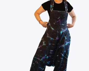 May include: A person wearing a black shirt and tie-dye overalls with a bright orange face mask. The overalls have a black background with blue and purple tie-dye patterns.