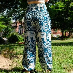May include: Teal blue pants with a white elephant print. The pants have a wide leg and an elastic waistband.