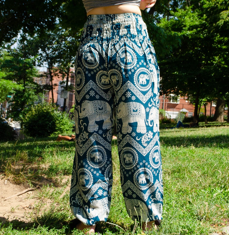 May include: Teal blue pants with a white elephant print. The pants have a wide leg and an elastic waistband.