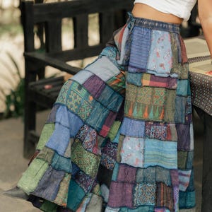May include: Wide-leg pants featuring a patchwork design composed of various fabric squares in shades of blue, green, and purple. The garment includes an elasticized waistband with a drawstring tie and displays a mix of solid, striped, and patterned textiles.