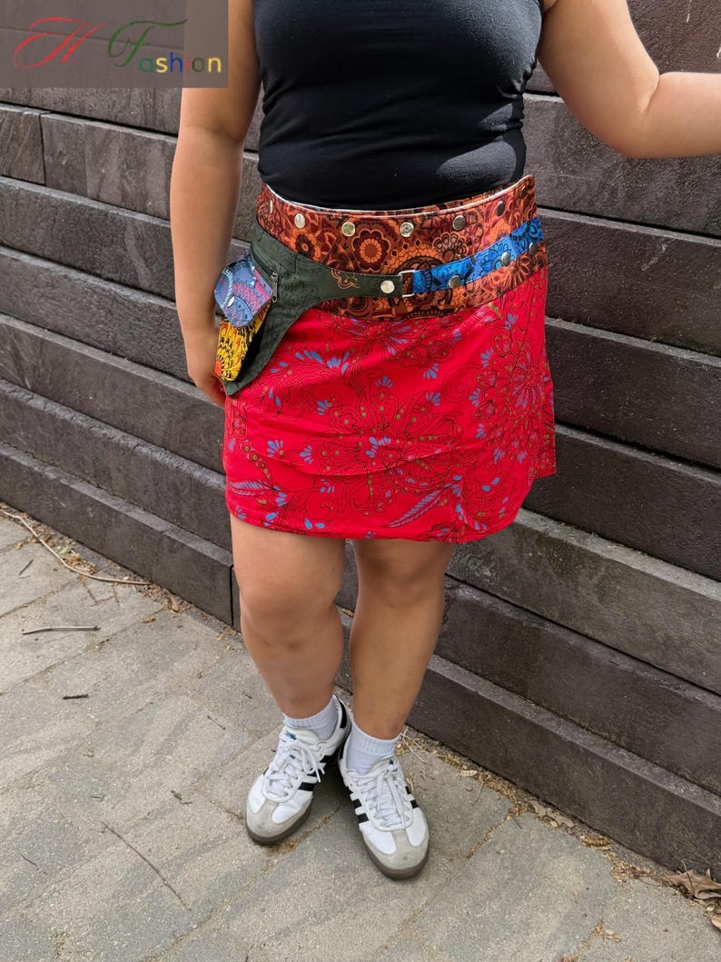 Puede incluir: Minifalda roja con estampado floral y ri&ntilde;onera multicolor. El cintur&oacute;n tiene un dise&ntilde;o marr&oacute;n, naranja y azul. La persona lleva un top negro y zapatillas blancas.