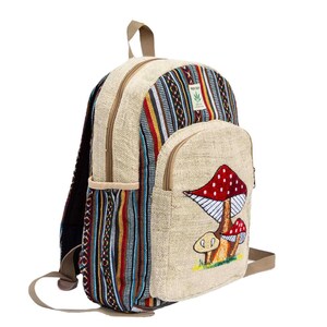 May include: A beige hemp backpack with a colorful striped pattern on one side and a red and white mushroom design on the other side. The backpack has a zippered pocket on the front and a top handle.