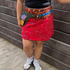 Puede incluir: Una falda roja estampada con un cintur&oacute;n multicolor y una peque&ntilde;a bolsa adjunta. La falda tiene un dise&ntilde;o floral y se combina con una camiseta negra y zapatillas blancas.