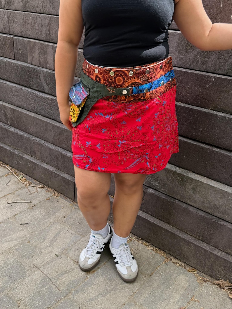 Puede incluir: Una falda roja estampada con un cintur&oacute;n multicolor y una peque&ntilde;a bolsa adjunta. La falda tiene un dise&ntilde;o floral y se combina con una camiseta negra y zapatillas blancas.