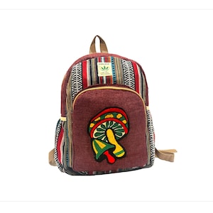 May include: A brown canvas backpack with a colorful striped pattern and a mushroom embroidered on the front. The backpack has a brown leather strap and a small patch with the text "Pure Hemp" and a green leaf.