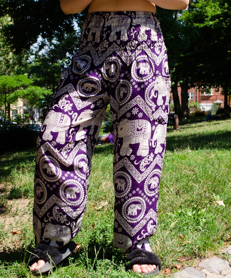 May include: Purple and white patterned pants with an elephant design. The pants are loose fitting and have a wide leg.