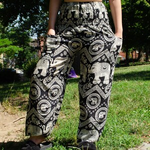 May include: Black pants with a white elephant print. The pants have a wide leg and a drawstring waist.
