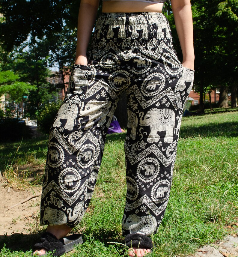May include: Black pants with a white elephant print. The pants have a wide leg and a drawstring waist.