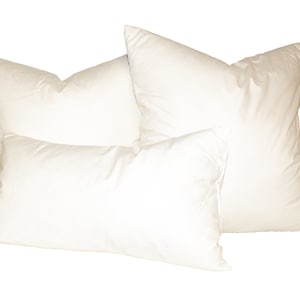 May include: Three white pillows of different sizes, arranged in a stack. The pillows are made of a soft, fluffy material and are perfect for sleeping or lounging.
